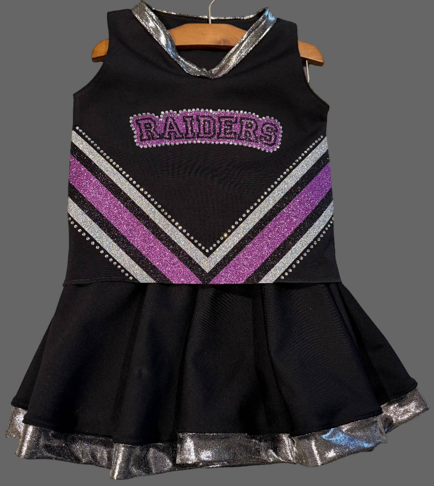 Black cheerleader outfit with purple and silver accents on a hanger.